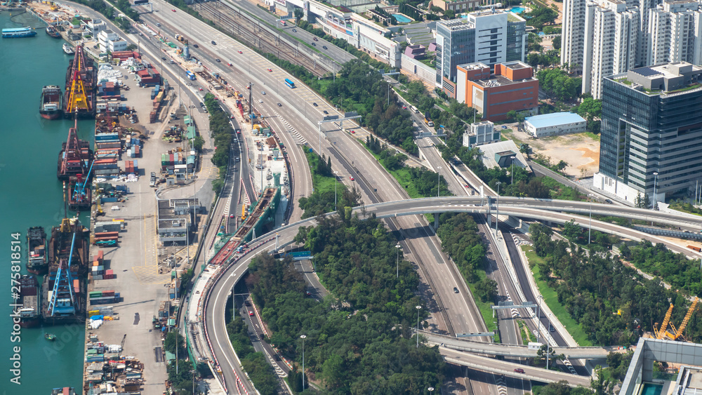 Fototapeta premium High view of Hong Kong skyline cityscape with car traffic on the road and container ship at industral port