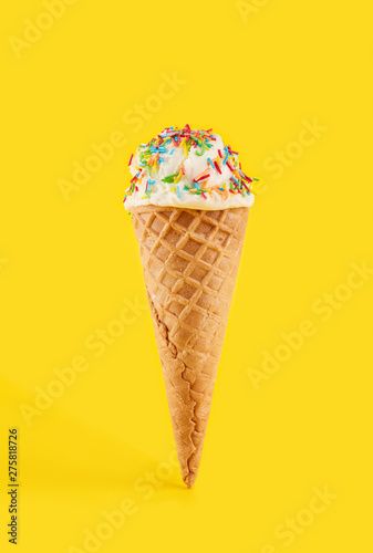 white ice cream ball in a Waffle Cone on a yellow Background. Fruit ice cream in a waffle cone.