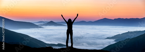 Glückliche Frau auf einem Gipfel über der Nebeldecke photo