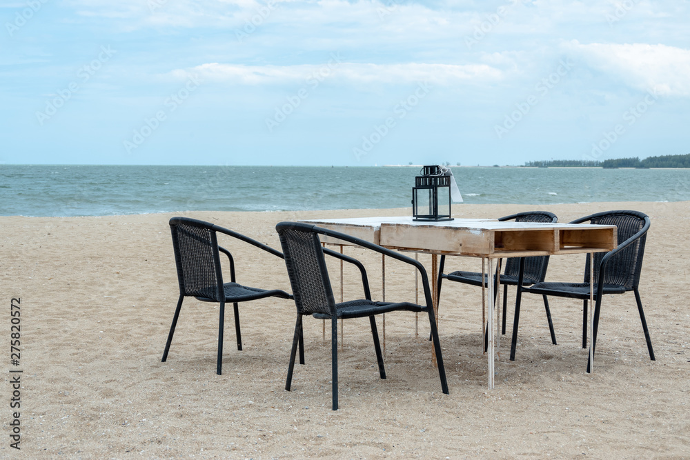 Empty wooden table and chair on the beach for family dinner with blue sea.