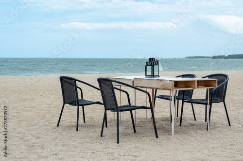 Empty wooden table and chair on the beach for family dinner with blue sea.