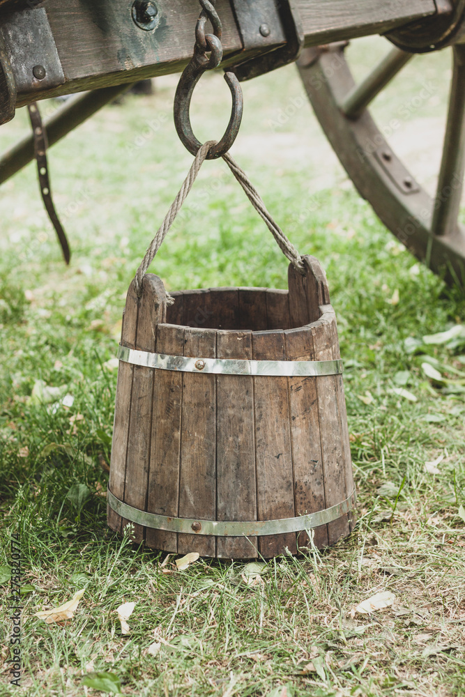 wooden old bucket stands on the ground with green grass wooden old bucket stands on the ground with green grass