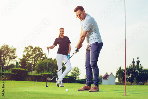 Happy couple playing golf at the club