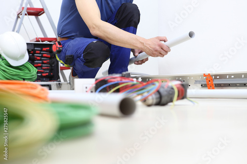 electrician at work with the plastic pipe in his hand to pass the electric cables to the sockets, electrical wiring