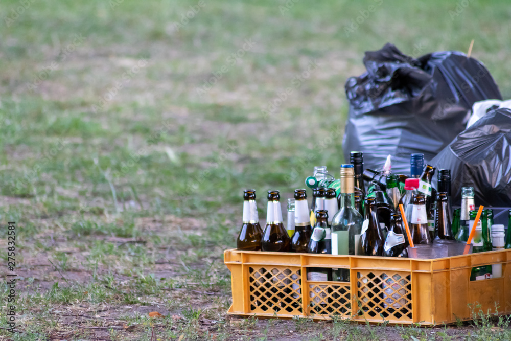 Leere Bierflaschen und leere Weinflaschen stehen nach einer Party neben  einem grauen Müllsack als Zeichen für Feiern, Alkoholgenuss, Alkoholsucht  und Altglas-Verwertung Stock-Foto | Adobe Stock