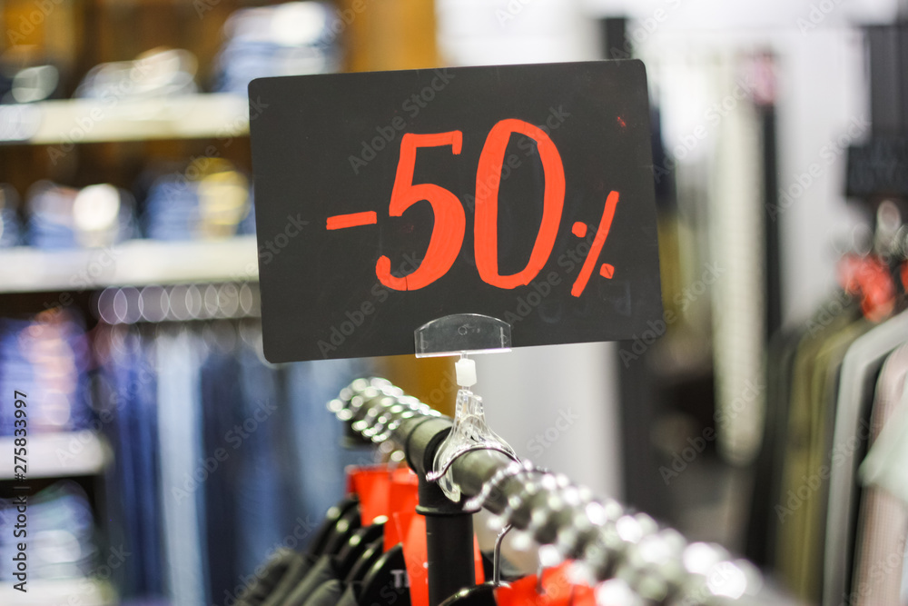 Obraz premium Close-up red tag sale 50 percent discount in a clothing store. Big reductions concept for Black Friday and Holiday season sale.