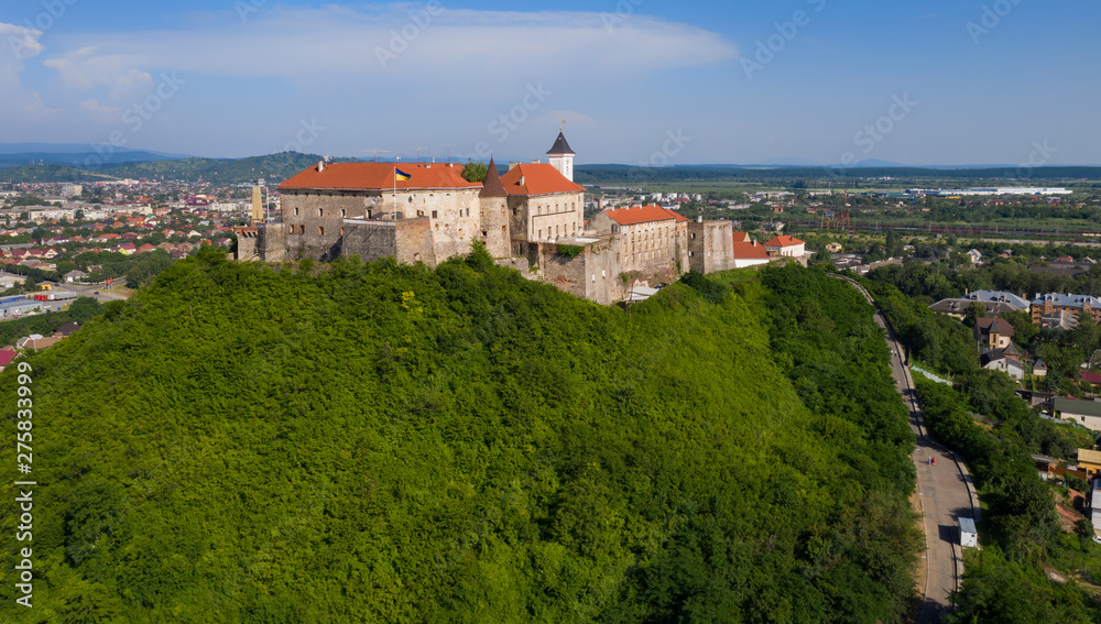 Picturesque view to the Palanok Castle with the red roofs under the blue sky in Mukachevo, Transcarpathian region in Ukraine. Aerial drone photo.
