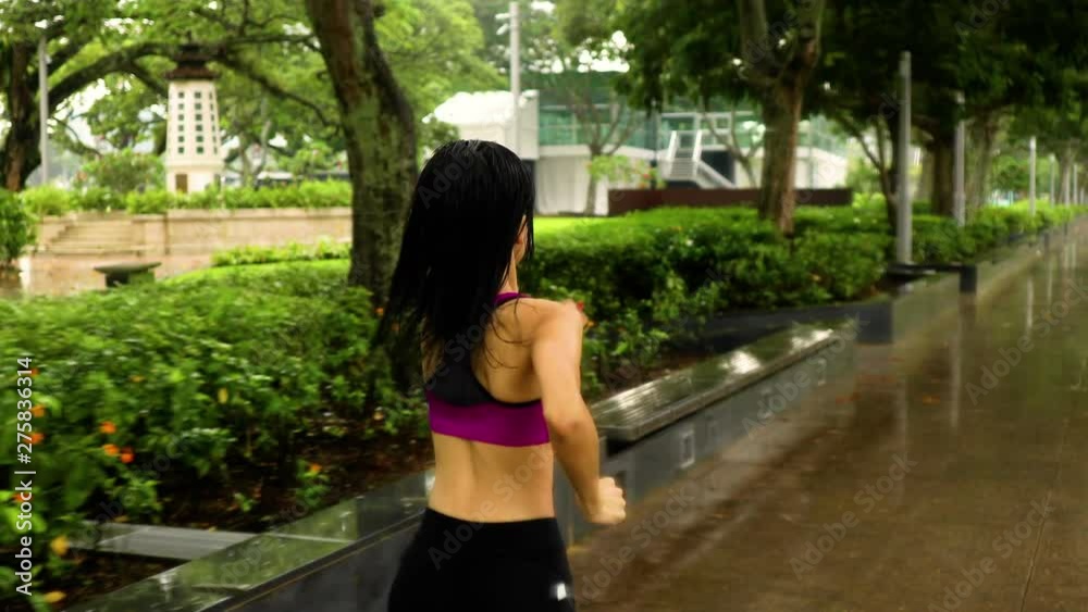 Middle-aged Asian woman jogging in the rain in Singapore