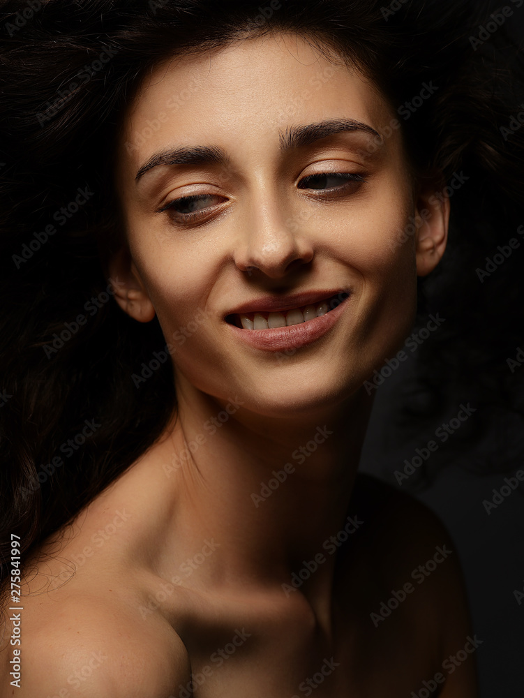 portrait of a young beautiful sexy girl with curly hair on a dark background