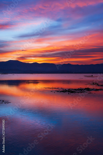 Dramatic clouds and sunset sky over the lake and mountain in backgrounds.