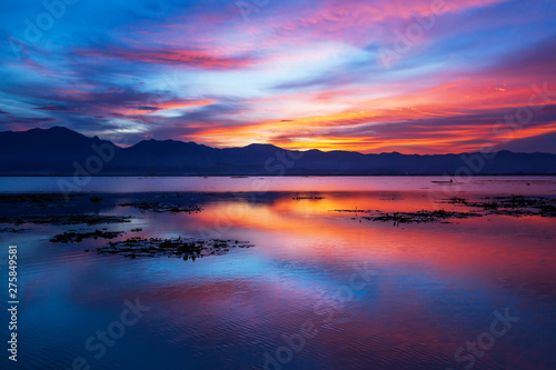 Dramatic clouds and sunset sky over the lake and mountain in backgrounds.