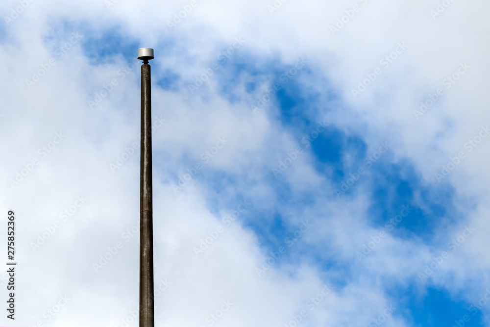 A large, empty flagpole, against a partially cloudy sky. The flagpole is metal, but does not have a flag or rigging. A large, empty flagpole, against a partially cloudy sky. The flagpole is metal, but does not have a flag or rigging.