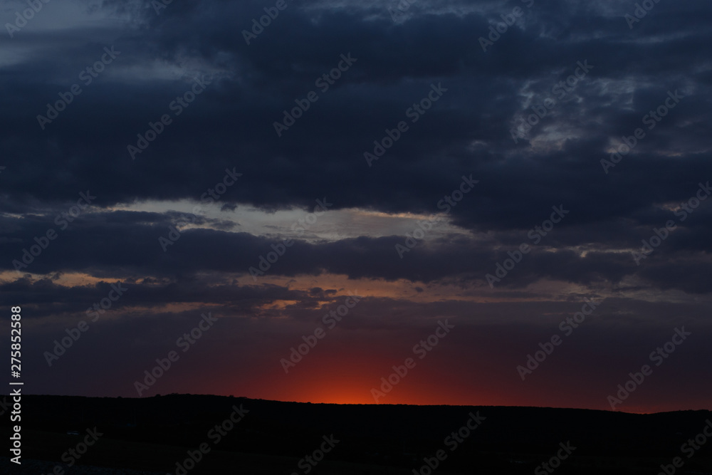 The sun shines early in the morning beyond the earth. Bright and even glow orange pink. On the sky clouds of incredible shape. The sun shines early in the morning beyond the earth. Bright and even glow orange pink. On the sky clouds of incredible shape.