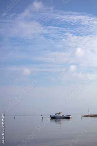 Colorful Fishing Boat on Sea with Reflections Over Blue Cloudy Sky at Morning Time