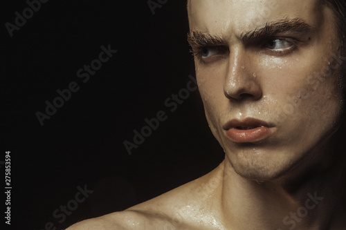 Handsome wet sport sexy stripped guy portrait with waterdrops and smoke on isolated black background