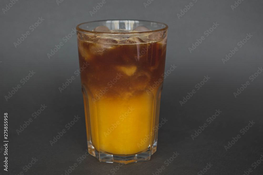A large transparent glass filled with cold summer drink Latte with orange juice cooked in a coffee shop of the third wave. gray, isolated background, photo for the menu A large transparent glass filled with cold summer drink Latte with orange juice cooked in a coffee shop of the third wave. gray, isolated background, photo for the menu