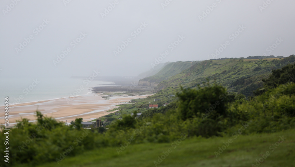 Low tide at the beaches of Arromanches, Normandy, a dark day with clouds remembering the soldiers who died storming the beach. 