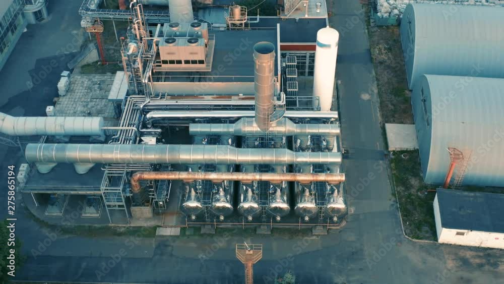 Aerial side view of the modern factory with chrome pipeline and chimney Aerial side view of the modern factory with chrome pipeline and chimney