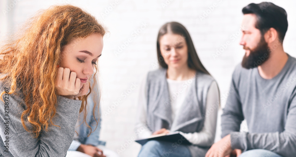 Depressed pensive woman sitting at rehab group therapy Depressed pensive woman sitting at rehab group therapy