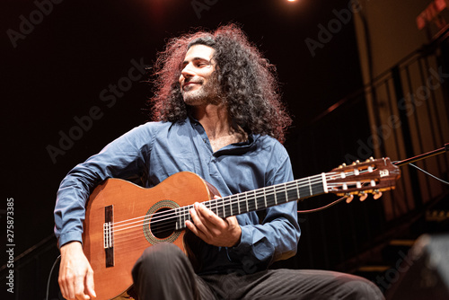 handsome man with long hair playing classical guitar