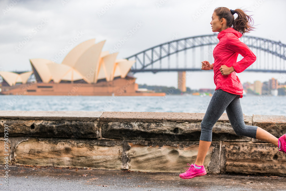 Naklejka premium Biegaczka pasuje do kobiety uprawiającej aktywny styl życia, uprawiającej jogging w Sydney Harbour przy słynnej atrakcji turystycznej Opery. Życie w mieście.