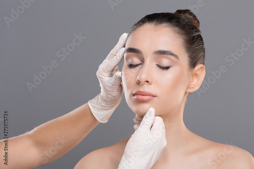 Young woman on consultation at beautician, grey background photo