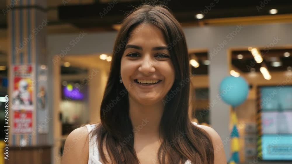 Young cheerful caucasian girl with brunette hair smiling in the mall Young cheerful caucasian girl with brunette hair smiling in the mall