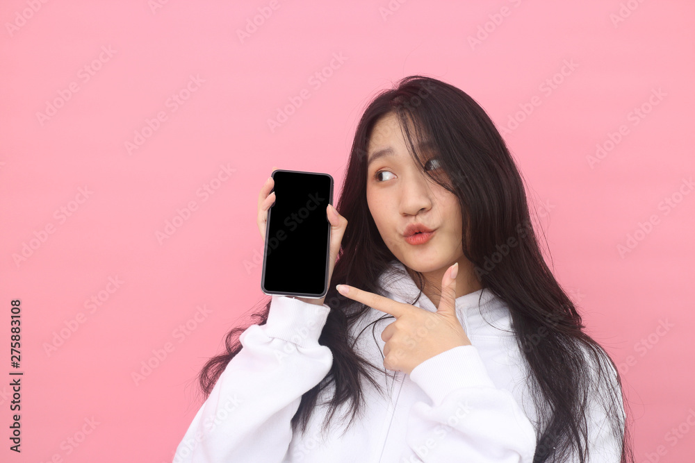 happy excited  glad to receive text message informing about salary, rejoices good news, stares at mobile phone, actively from happiness, Beautiful Asian models over  pink  background for advertising c