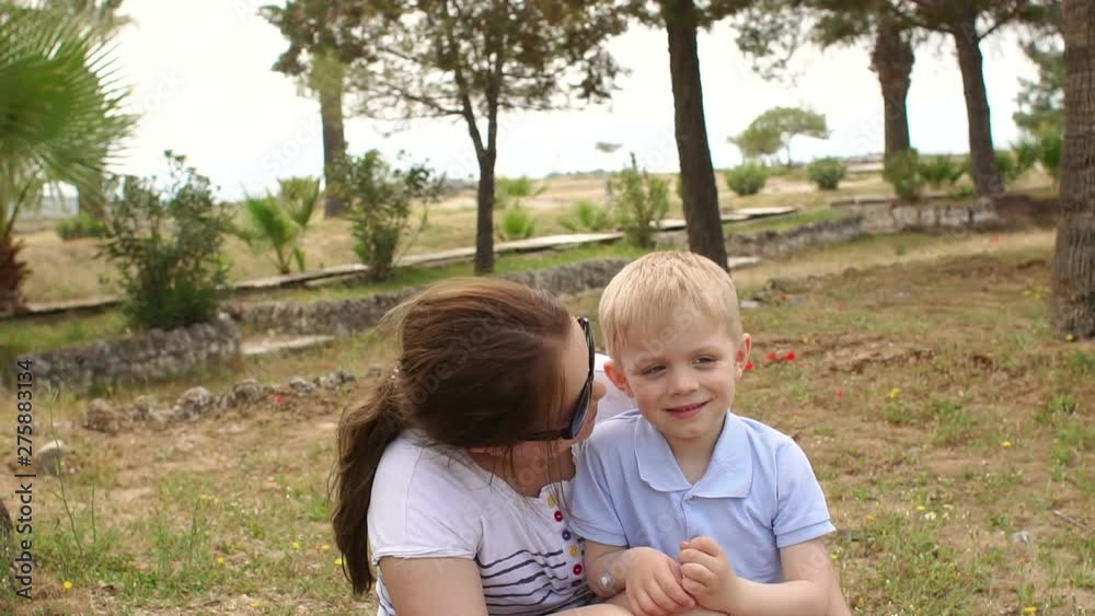 Portrait of mother and son in the Park in the summer against the palm trees, mother hugs her son and kisses. Slow motion. Summer holiday. Portrait of mother and son in the Park in the summer against the palm trees, mother hugs her son and kisses. Slow motion. Summer holiday.