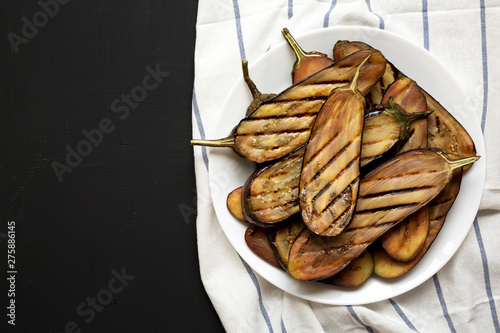 Grilled eggplant on a white plate on a black background. Copy space. photo