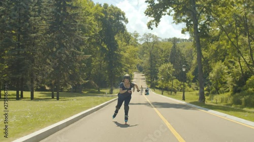 Wallpaper Mural Happy fearless female in protective equipment rollerblading at speed up and down park alley enjoying freedom of extreme ride. Joyful woman riding roller blades in green park on sunny windy day. Torontodigital.ca