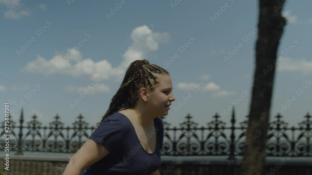 Portrait of happy female with long ponytail from afro-braids enjoying freedom and speed rollerskating on windy sunny day. Positive woman roller riding in summer park while wind waving her hair. Portrait of happy female with long ponytail from afro-braids enjoying freedom and speed rollerskating on windy sunny day. Positive woman roller riding in summer park while wind waving her hair.