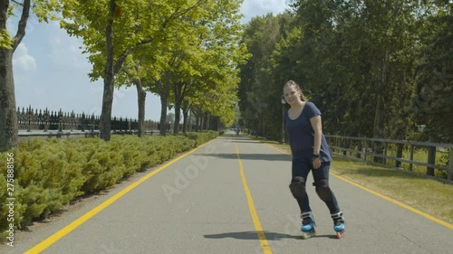 Wallpaper Mural Joyful woman in protective equipment rollerblading along well-kept summer park alley. Positive female roller with ponytail from afro-braids riding among green trees enjoying outdoor summer leisure. Torontodigital.ca