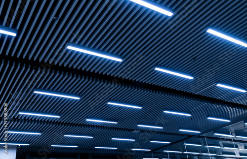 Leading lines and low light view. Fluorescent lamps open in row on the ceiling beautiful and modern inside the building.