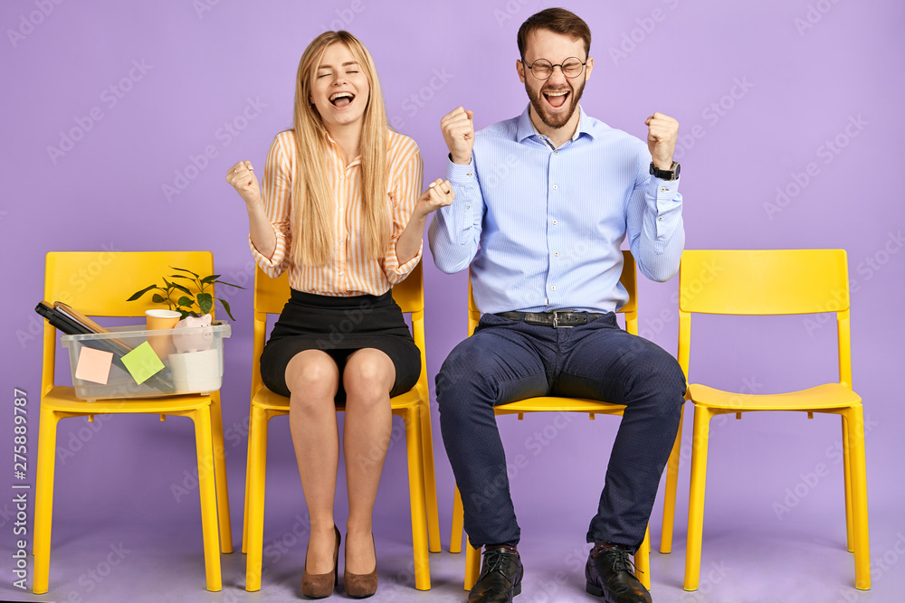Obraz premium happy young blonde woman with closed eyes and man in round eyewear sitting extremely excited by great news and waiting for job interview