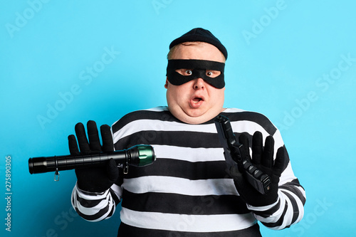 Photo scared burglar doesn't want tobe caught by policeman, isolated blue background