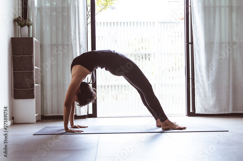 Fototapeta Naklejka Na Ścianę i Meble -  Young woman practicing yoga in  gray background.Young people do yoga indoor