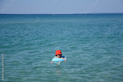 Little boy with inflatable ring swimming in the sea. Child with a floating ring enjoy in water © Ivan