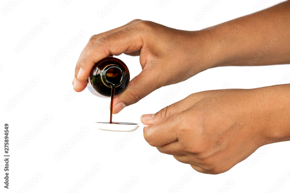 medical syrup flowing from a bottle into a spoon in the hands medical syrup flowing from a bottle into a spoon in the hands