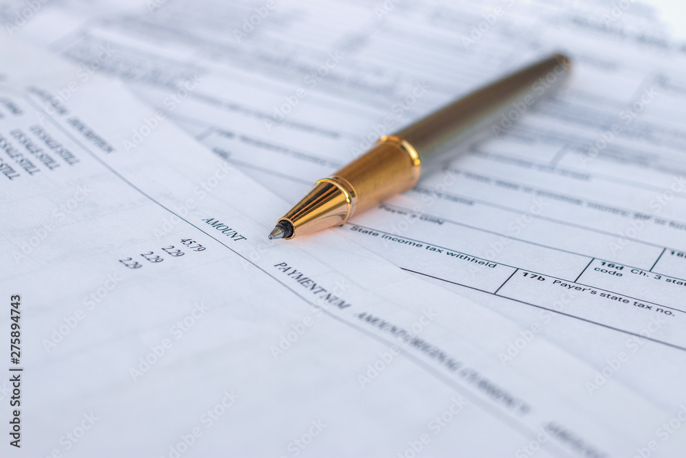 Low angle view of golden pen lying on white sheet of paper in a folder with another set of paperwork Low angle view of golden pen lying on white sheet of paper in a folder with another set of paperwork