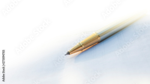 Low angle view of golden pen lying on white sheet of paper in a folder with another set of paperwork