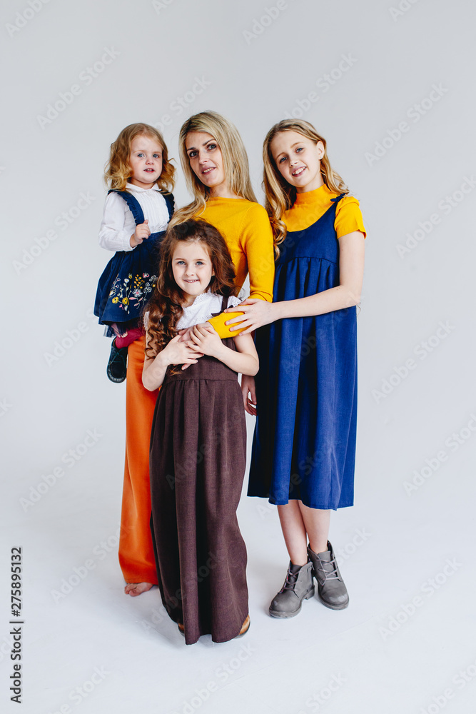 Fototapeta premium A mother with three cute daughters playing with wooden toy train. A family of four girls. Girls hugging their mother