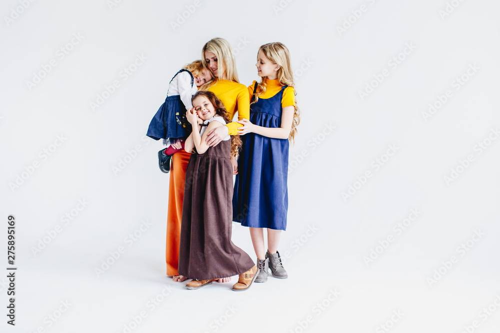 A mother with three cute daughters playing with wooden toy train. A family of four girls. Girls hugging their mother