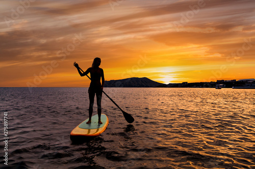 Stand up paddle boarding on a quiet sea with warm summer sunset colors. photo