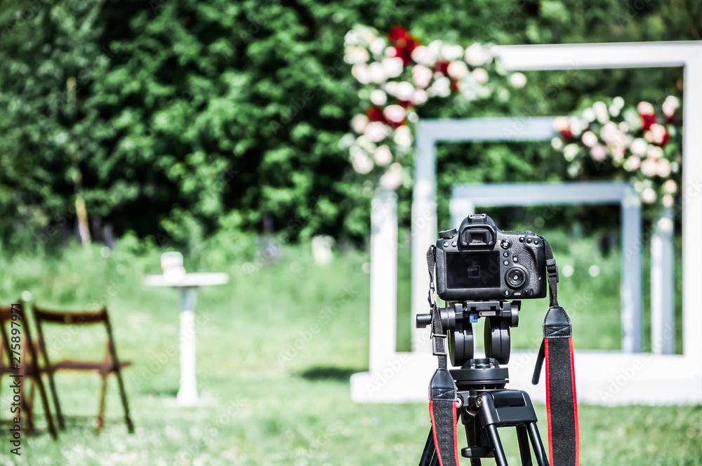 A photo camera mounted on a tripod is ready to shoot a festive wedding ceremony. A photo camera mounted on a tripod is ready to shoot a festive wedding ceremony.