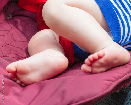The legs of the baby lying in the stroller