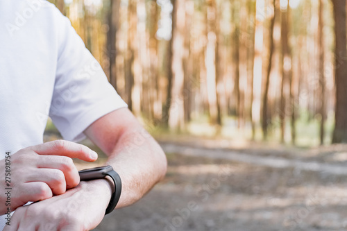 Using smart watch outdoors for walking or jogging. Close-up of human hand with a smart watch in the forest