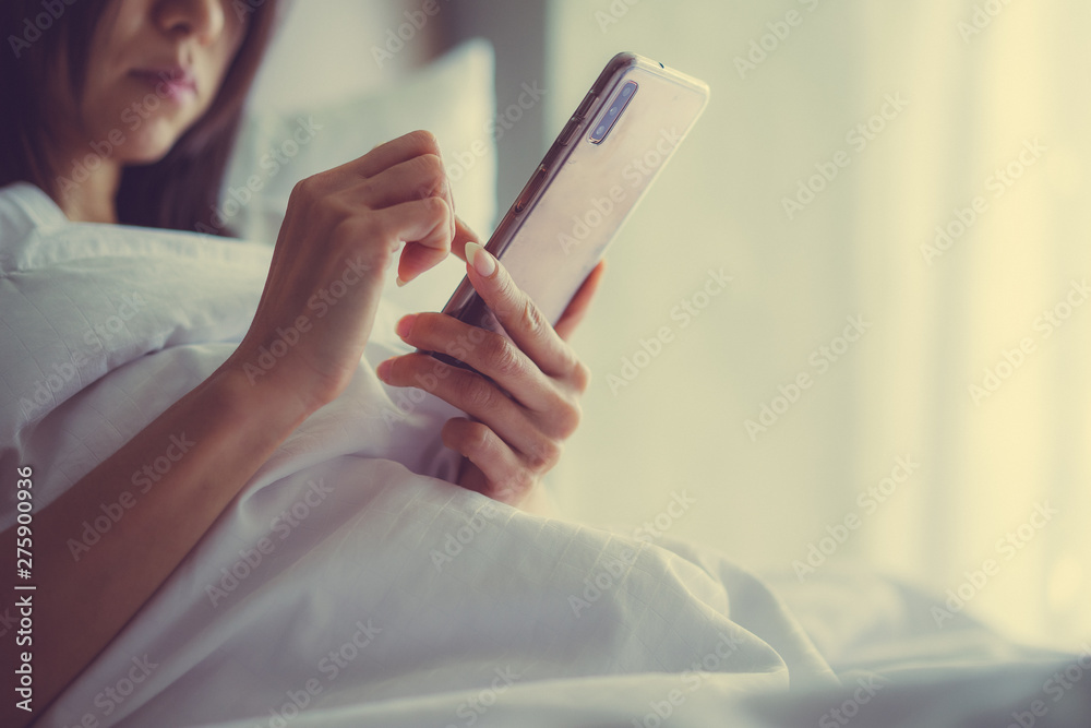 Asian Girl in bed room on the bed with the mobile phone.Closeup portrait of young sleepy exhausted woman lying in bed using smartphone, Asian Girl in bed room on the bed with the mobile phone.Closeup portrait of young sleepy exhausted woman lying in bed using smartphone,