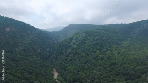 Panorama of wild mountain terrain. Hills covered with forest and river photo