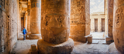 The tourist considers the hieroglyphs on the walls of the temple of Medinet Habu. Egypt, Luxor. The Mortuary Temple of Ramesses III at Medinet Habu is an important New Kingdom period structure